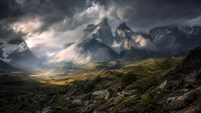 Paisaje montañoso dramático con nubes y valles verdes