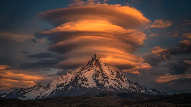 Nubes lenticulares sobre montaña nevada al atardecer