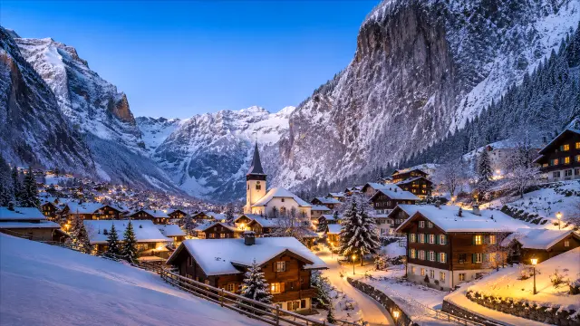 Pueblo alpino nevado con iglesia al atardecer