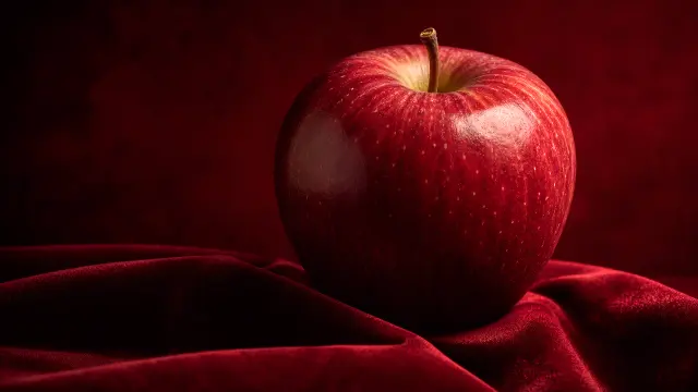 Manzana roja sobre tela de terciopelo rojo profundo — fondo materiales y ciencia IA