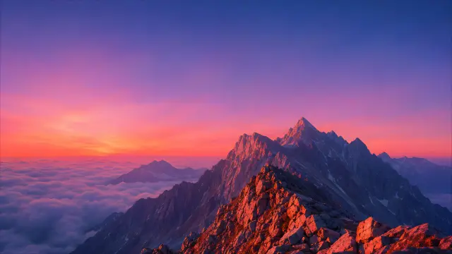 Cumbres rocosas sobre nubes con atardecer morado y rosa