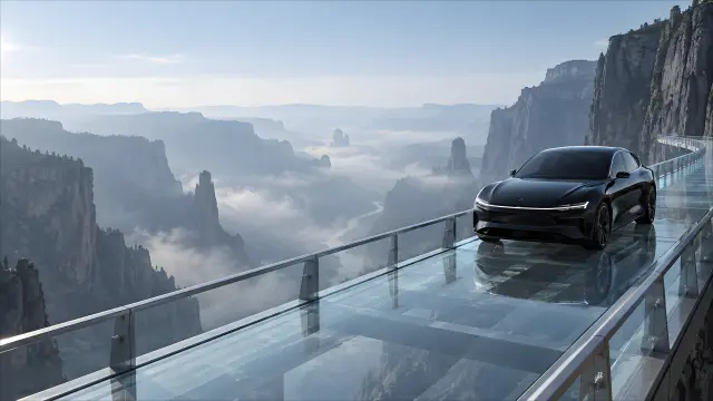 Coche eléctrico negro en pasarela de vidrio entre montañas