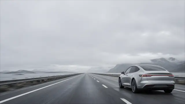Auto futurista plateado en carretera costera nublada