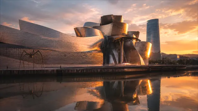 Guggenheim Bilbao al atardecer con rascacielos y reflejos