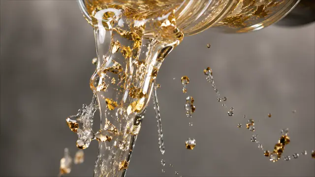 Liquido dorado con hojas metálicas cayendo