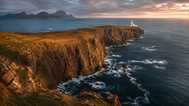 Farol en acantilados bajo atardecer dramático