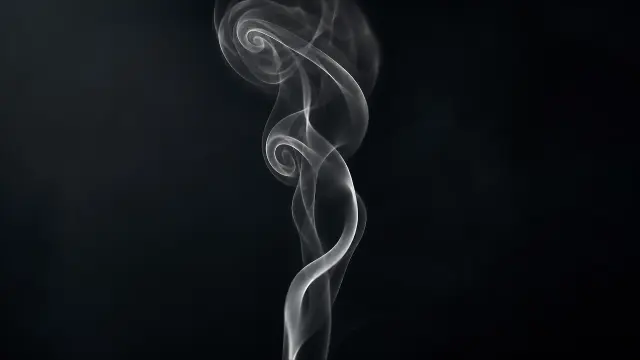 Espirales de humo gris oscuro sobre fondo negro suave
